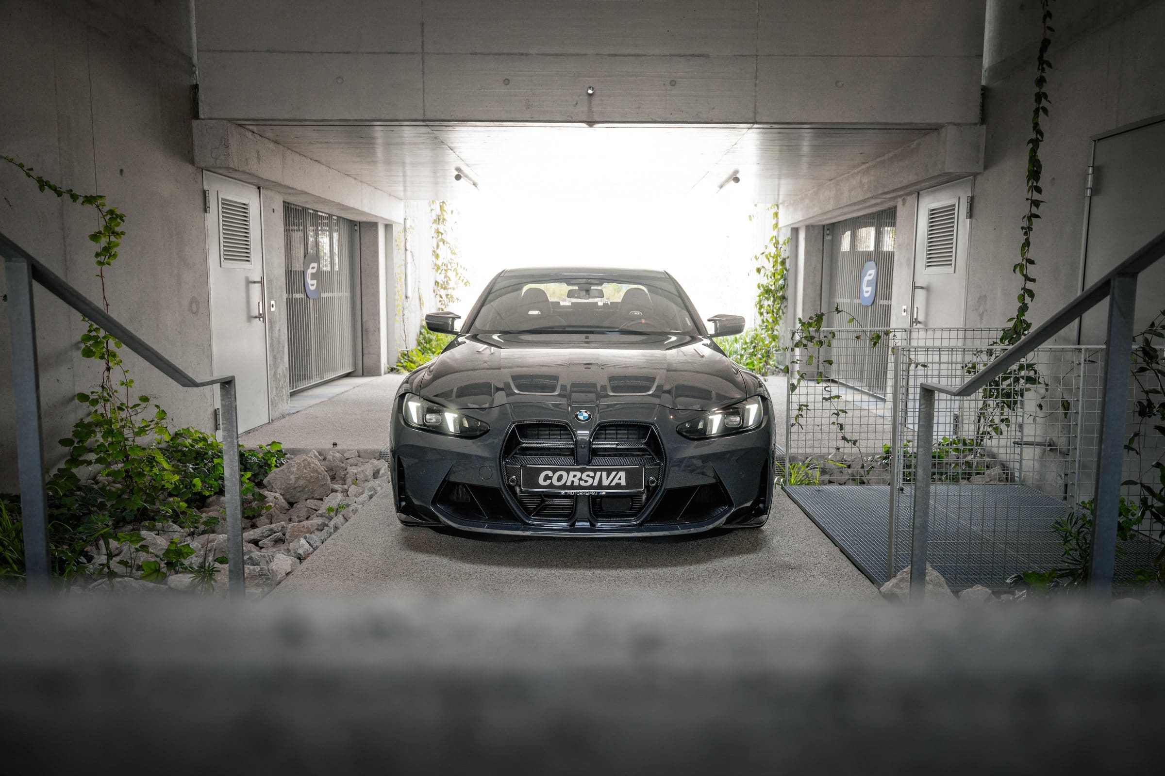 BMW M3 Competition du groupe Corsiva de face, au bout du passage du garage