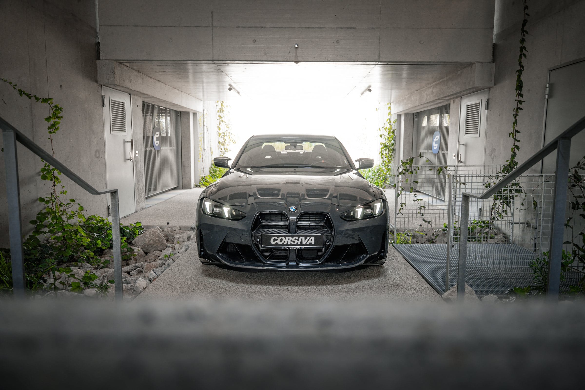 BMW M3 Competition du groupe Corsiva de face, au bout du passage du garage