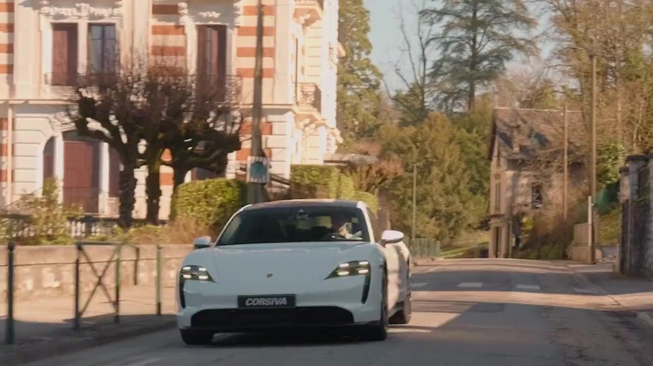 Porsche Taycan blanche du groupe Corsiva sur une route de ville