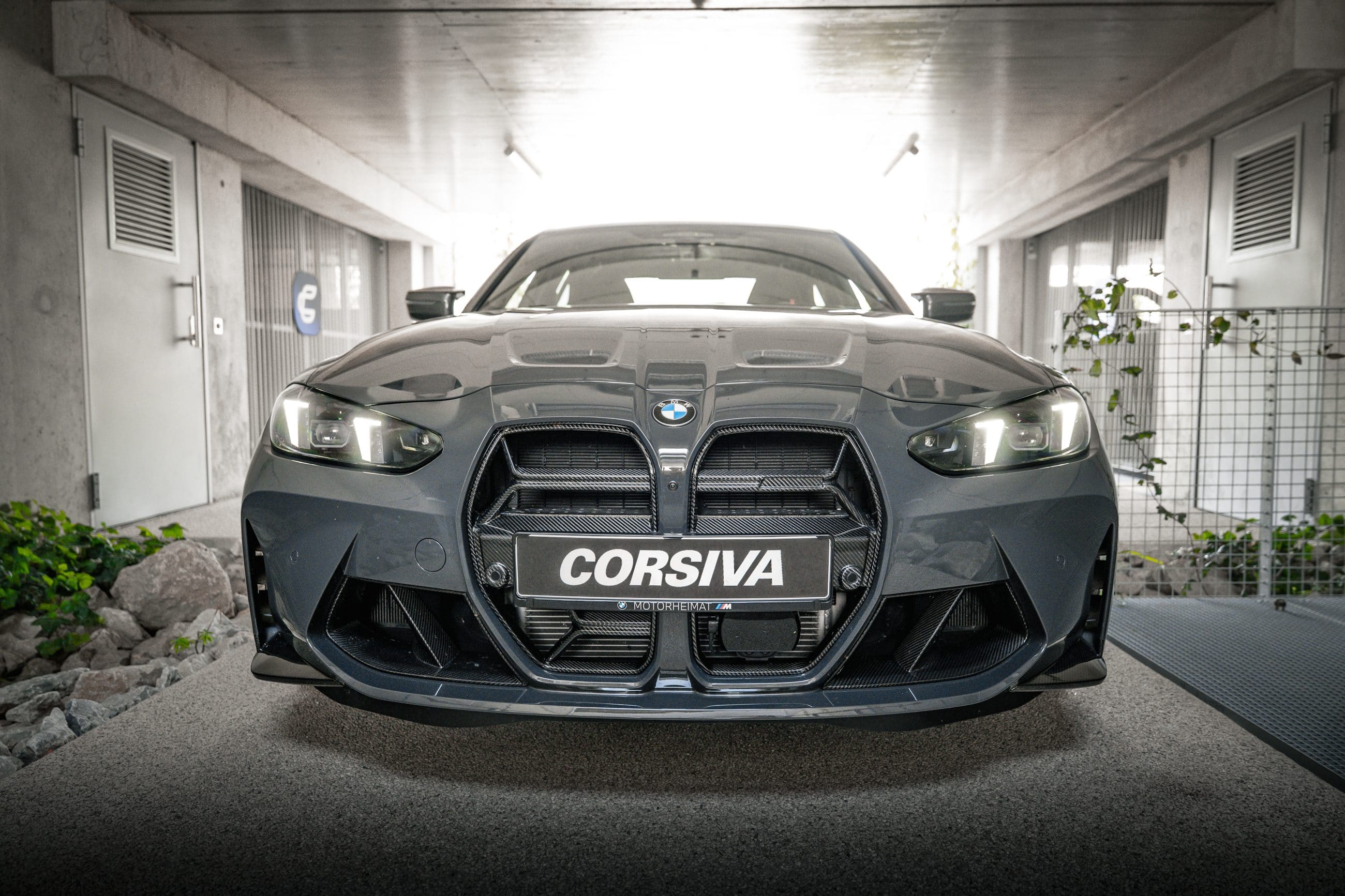 BMW M3 Competition du groupe Corsiva, de face, dans le passage du garage Corsiva