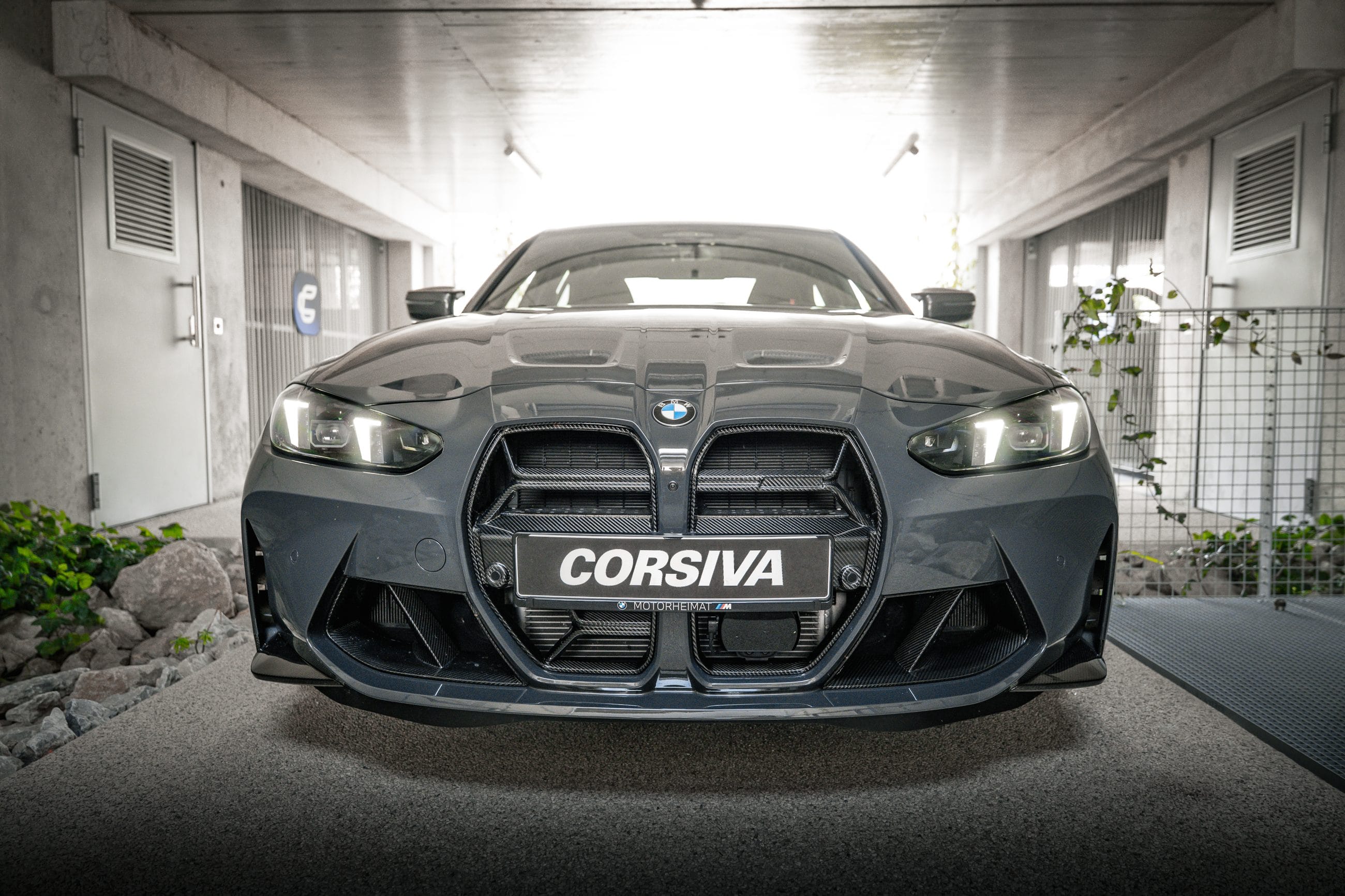 BMW M3 Competition du groupe Corsiva, de face, dans le passage du garage Corsiva